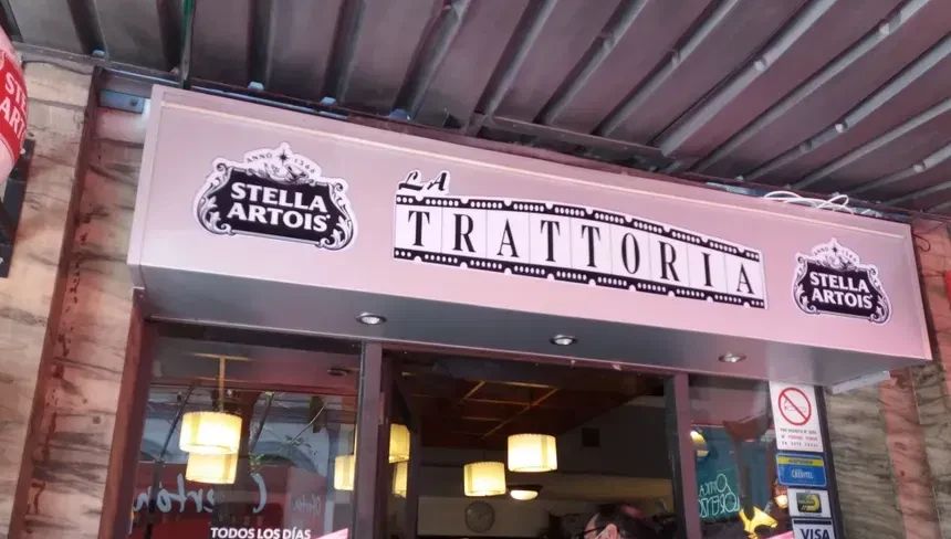 Cartel de La Trattoria sobre la entrada del local